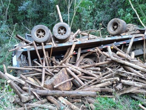 Motorista fica gravemente ferido após caminhão com toras tombar em ribanceira no Oeste