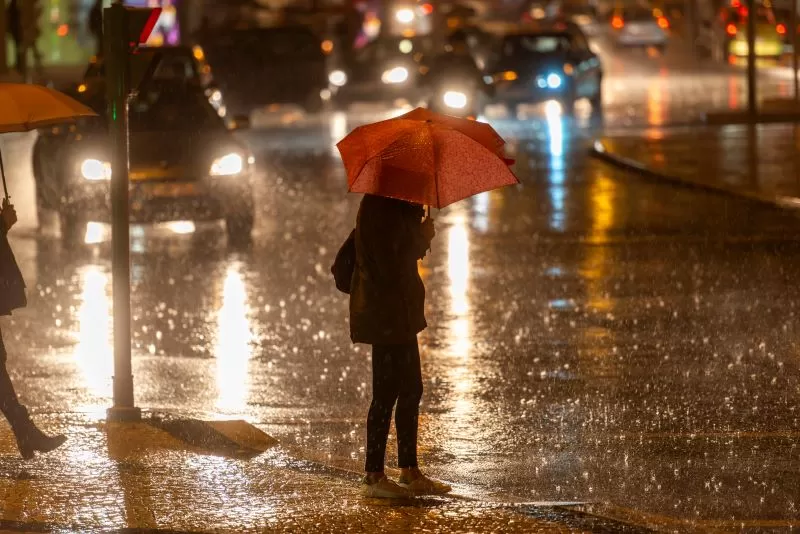 Mulher_atravessando_a_rua_segurando_um_guarda_chuva-convertido