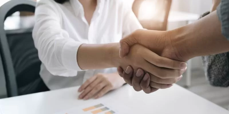 Empresaria_apertando_as_maos_em_um_acordo_de_cooperacao_empresarial_no_escritorio.-convertido