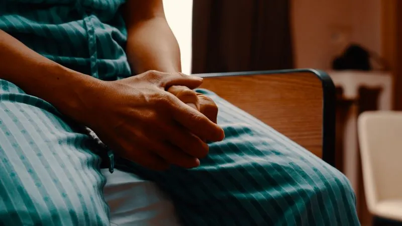 Homem_doente_sentado_na_cama_do_hospital-convertido